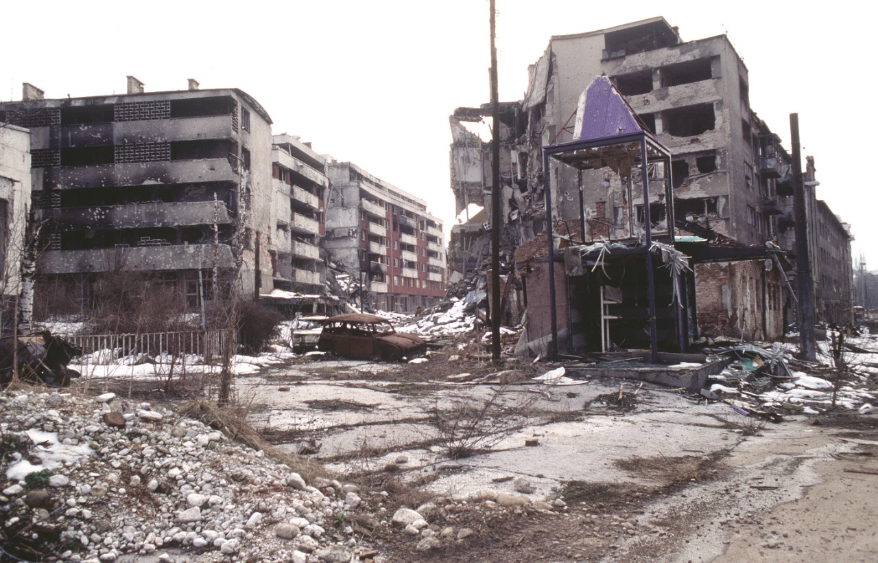 A street with rubble and bombed out and destroyed buildingss.