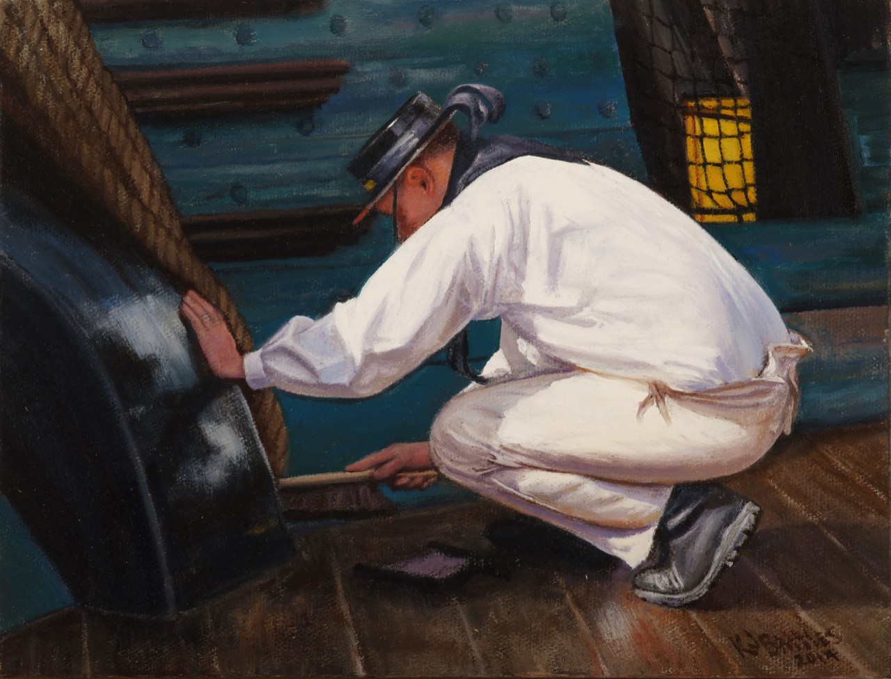 A sailor wearing a 19th century uniform is using a hand brush and a dust pan to sweep up around cannon