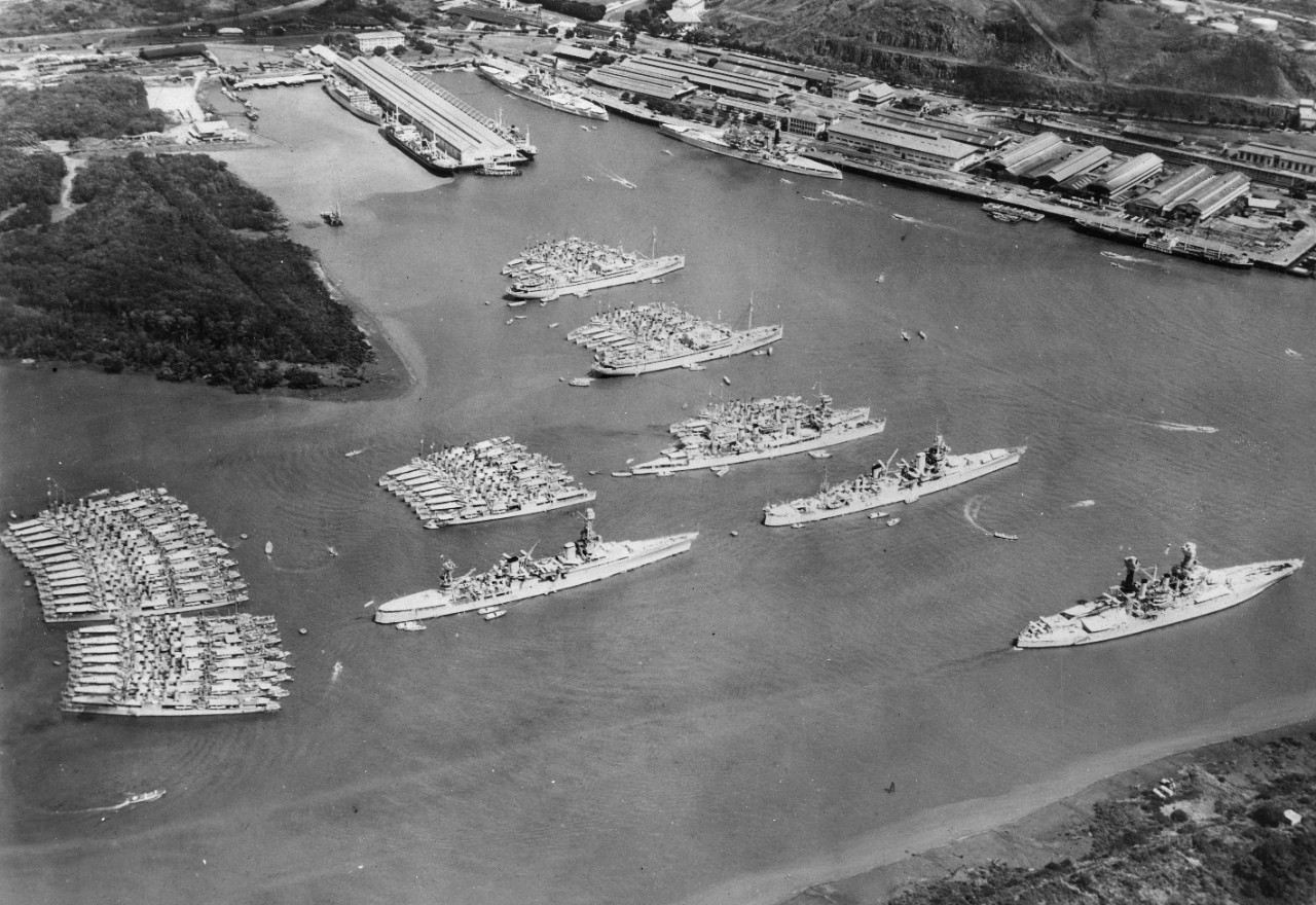 Two black and white images. One shows the Scouting Fleet at Balboa Harbor in the Canal zone,  1934, including USS Indianapolis (CA-35), USS Chicago (CA-29), USS Dobbin (AD-3), USS Whitney (AD-4), USS McFarland (DD-237), USS Goff (DD-247) and other ships including battleships, cruisers, destroyers, and auxiliaries. The other images shows USS Iowa (IX-6, BB-4) under fire as a target in the early 1920’s.