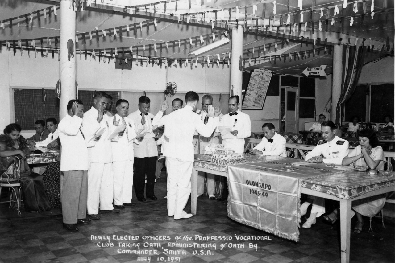 <p>2019.24.1 Newly Elected Officers of the Professional Vocational Club Taking Oath Administering of Oath by CDR Smith, USN May 10, 1951</p>