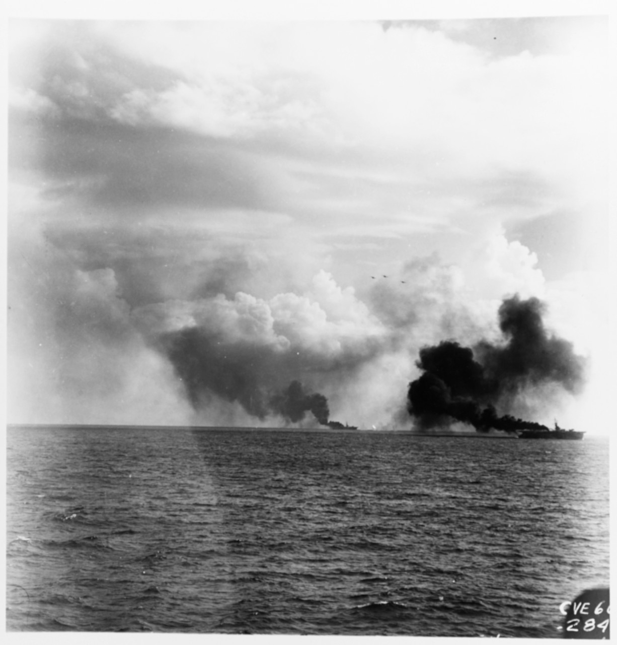 Two escort carriers of Carrier Division 25 under shell attack by the Japanese fleet. Note U.S. Navy planes overhead. Photo by USS White Plains (CVE-66).