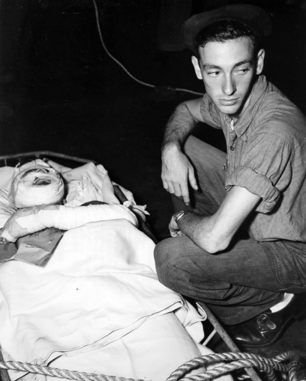 A crewman consoles a badly burned buddy before his transfer to a hospital ship. He had been injured when Ticonderoga was hit by a kamikaze off Formosa, 21 January, 1945. 
