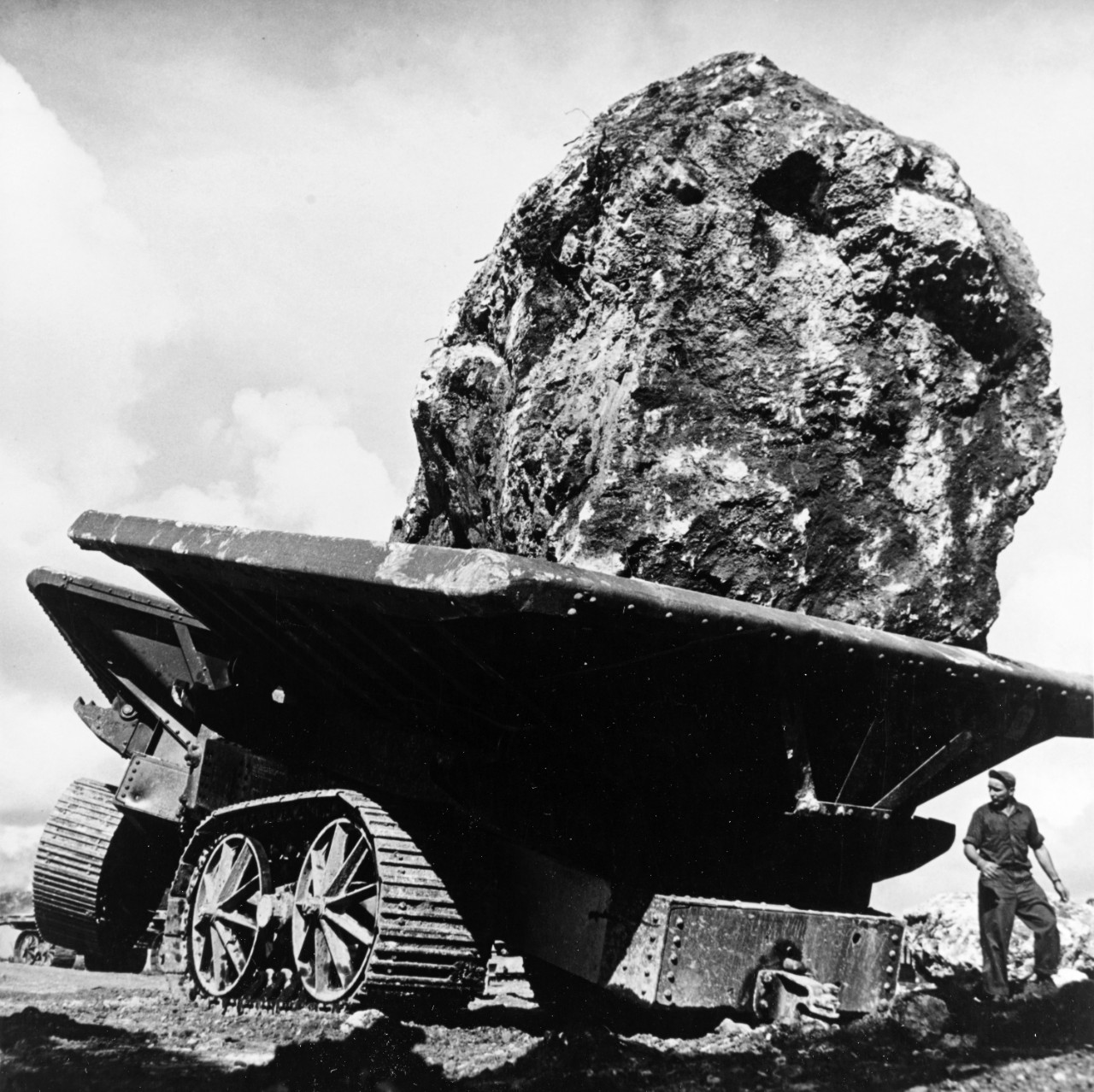 Large Caterpillar cart is positioned to dump a thirty ton boulder, as the 76th Construction Battalion builds Apra Harbor's two mile long breakwater, August 1945.