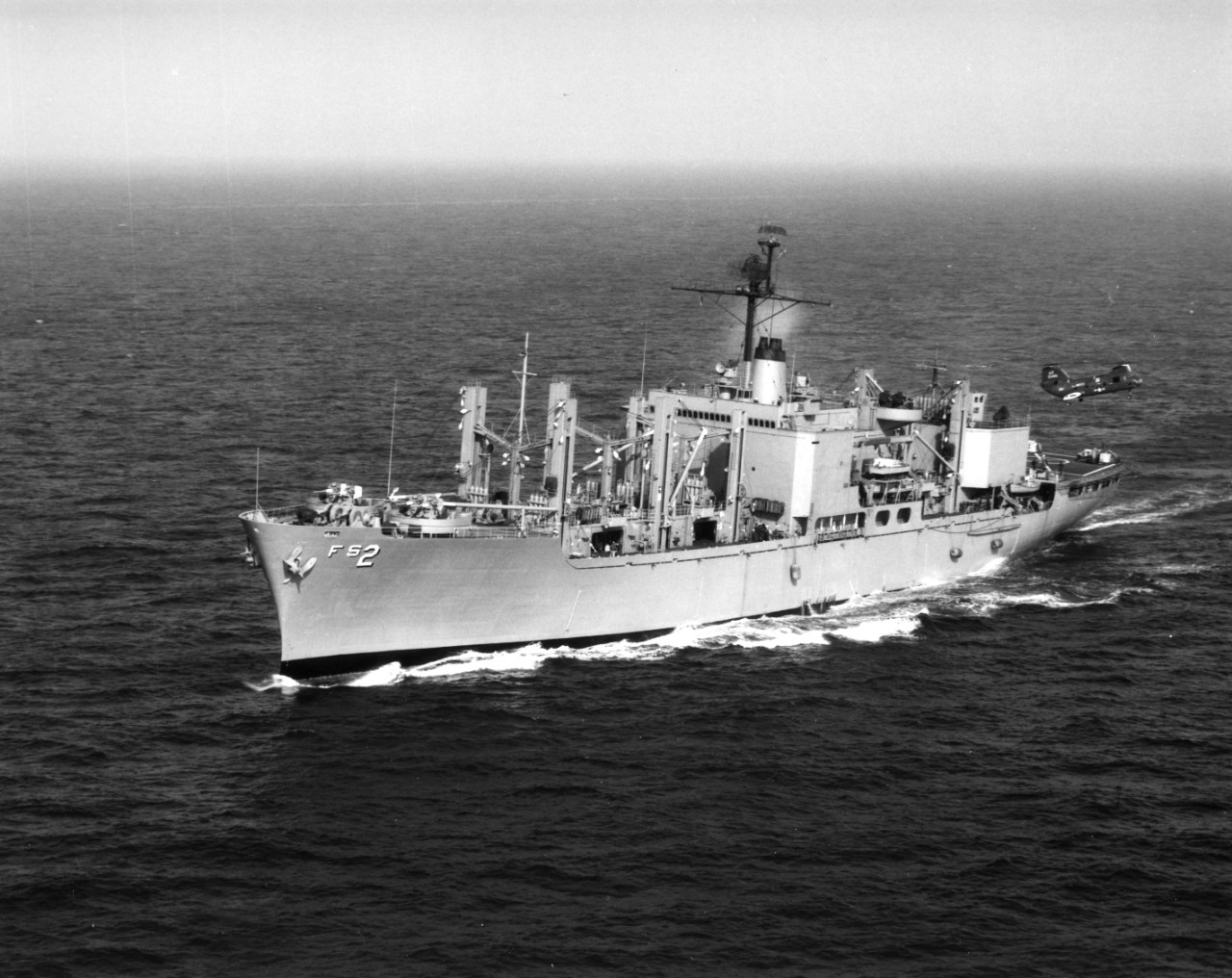 Aerial view of fast combat stores ship USS Sylvania (AFS-2) underway in the Mediterranean, April 1967. Vertical replenishment operations are being conducted by an H-46 Sea Knight helicopter.
