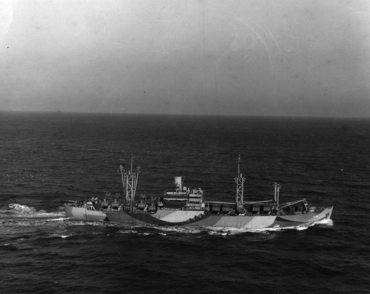 Starboard beam aerial view of attack cargo ship USS Tyrrell (AKA-80) underway in the South Atlantic Ocean just south of Norfolk, Virginia. She is painted in Measure 32 camouflage.