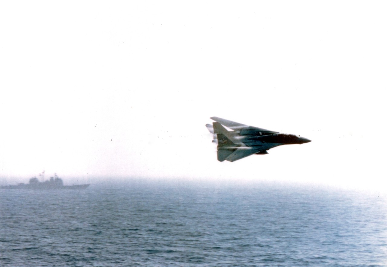 An F-14 Tomcat attached to Fighter Squadron 41 (VF-41) performs a high-speed fly-by near the guided missile cruiser USS Hue City (CG-68). Photographer PM2 Scott Moak.