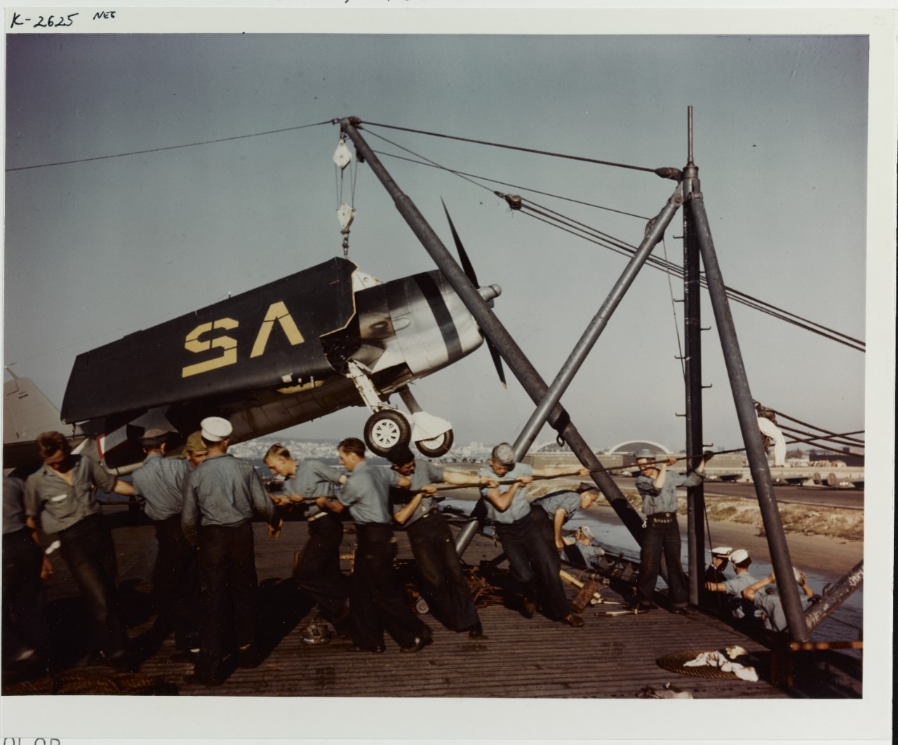 Men hoist a Grumman F6F-3 "Hellcat" fighter on board an aircraft carrier, circa mid-1943