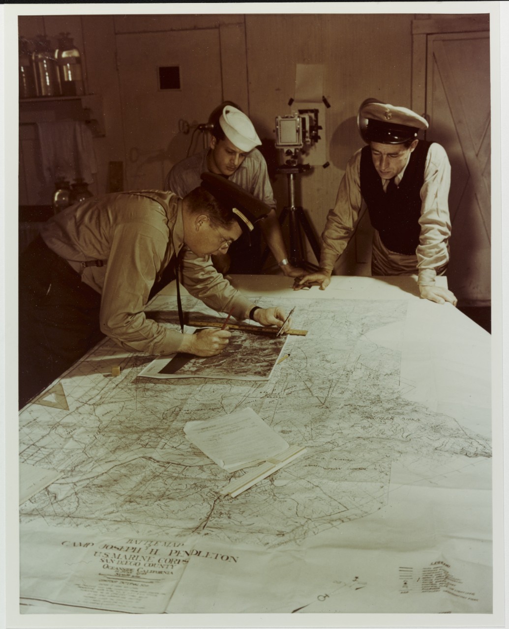 Photographic officer and assistants check details of aerial map of camp Joseph H. Pendleton, California, circa 1944-1945