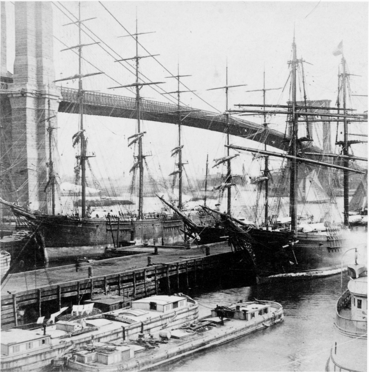 "The Glory of New York". Three-masted Wooden Sailing Merchant Ships at Piers, near the Brooklyn Bridge, circa the 1880s