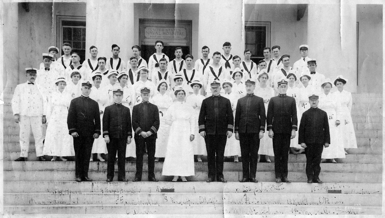 Medical officers, nurses and enlisted men of the Naval Hospital, Portsmouth, Virginia, circa 1914. Photographed by F.J. Conway. The nurse in the front row (center) is Elizabeth Leonhardt. Other nurses are (as numbered on the original print):     1. Ann Sands;     2. Lila Aman;     3. Delancey;     4. Hazel Hamlin;     5. Francis Winkler;     6. Dean;     7. Russell;     8. Mary Ann O'Keif;     9. unidentified;     10. Lilly Earl White;     11. Lela B. Coleman;     12. Myn Hoffman, who was the Nurse Corps' Superintendent in 1935-1938;     13. Kathleen O'Brien;     14. Marcella Southern;     15. Lappin;     16. Mullin.