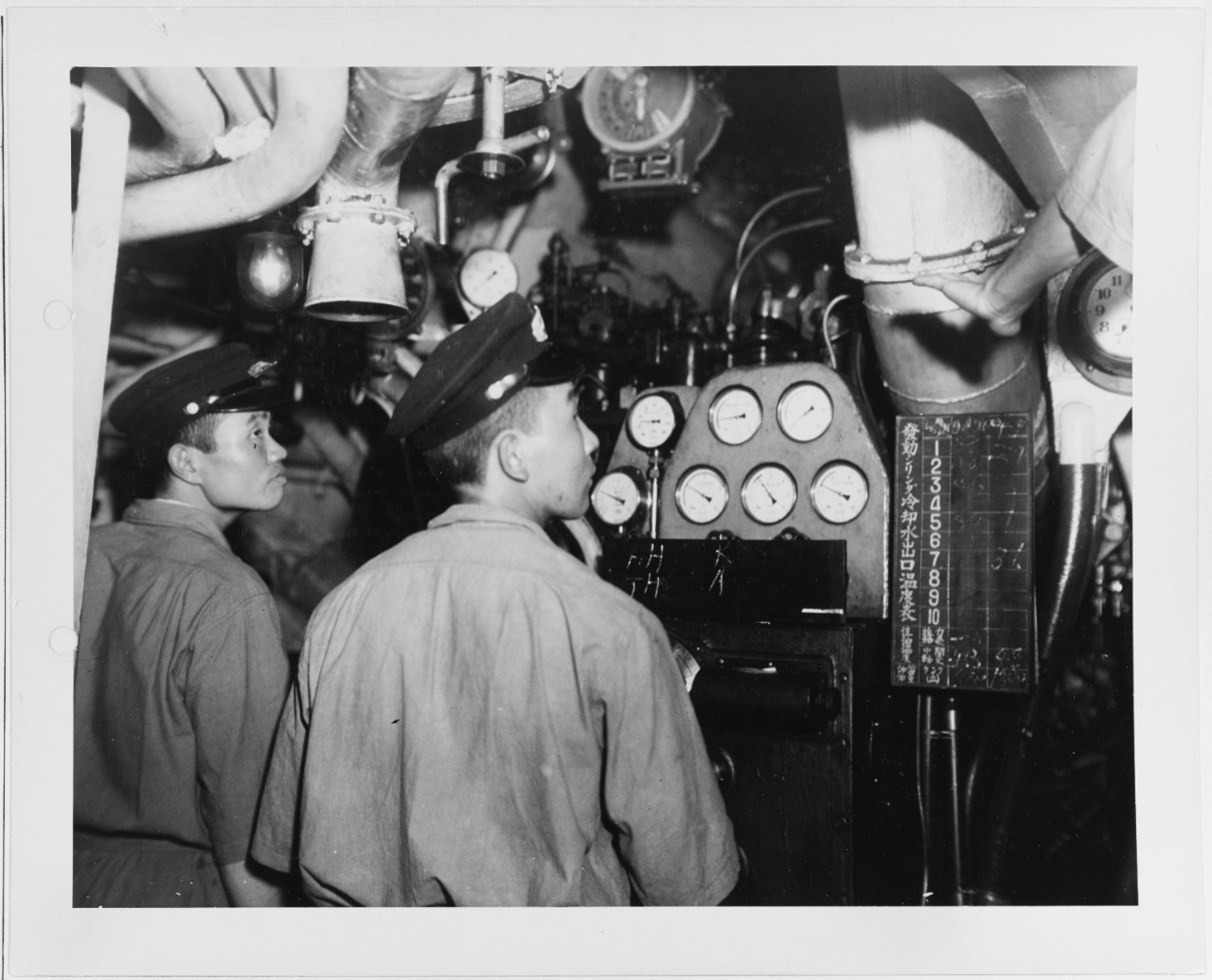 Men stand in Port Auxiliary Engine Room I-14 inside Japanese Submarine