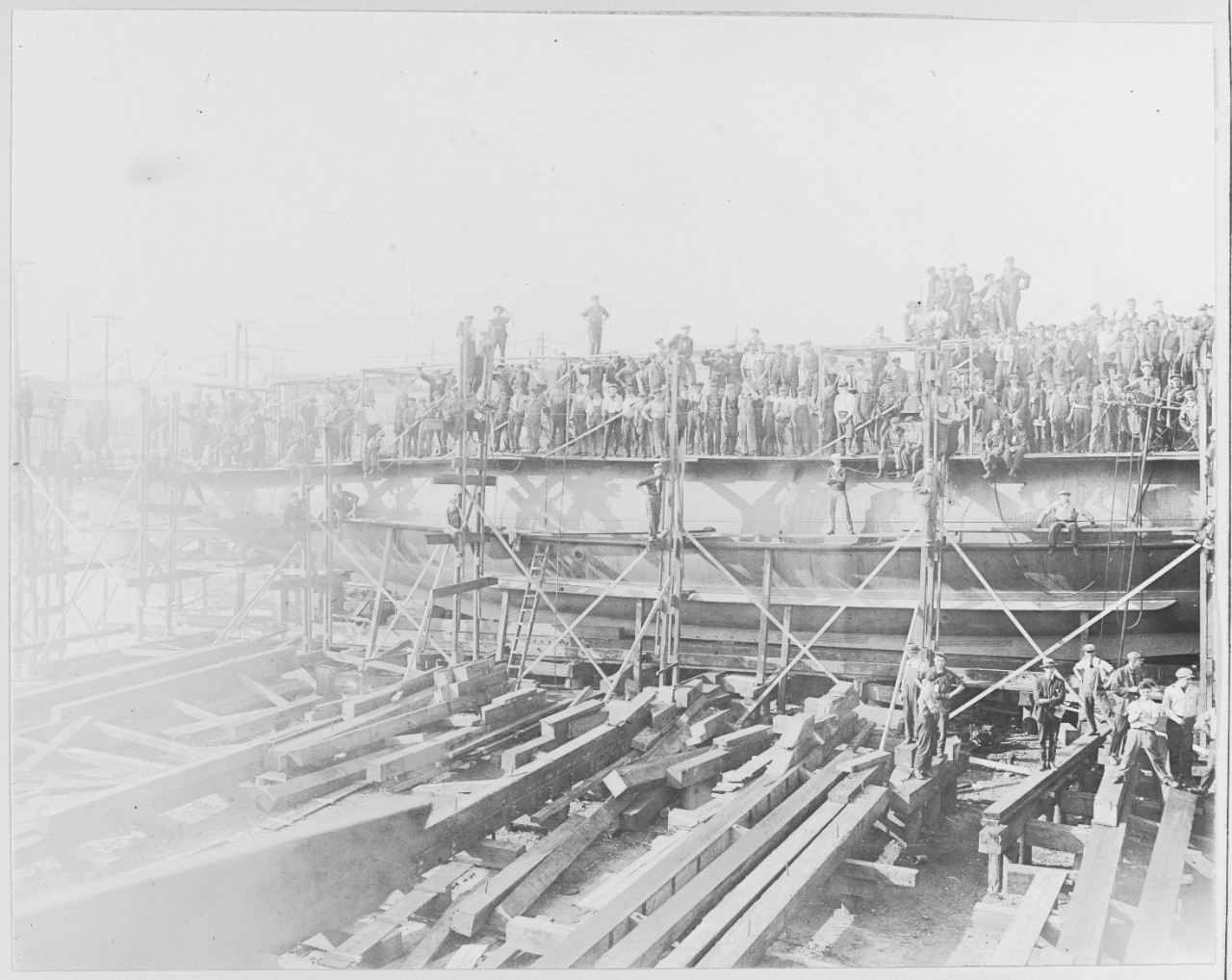 Men standing with wood structure, Lake Torpedo Boat Company. Bridgeport, Connecticut