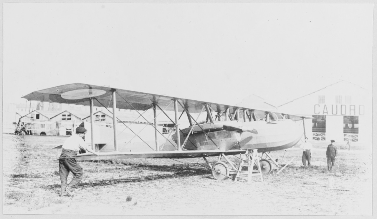 Men stand next to Caudron Plane, building behind says "Caudron"