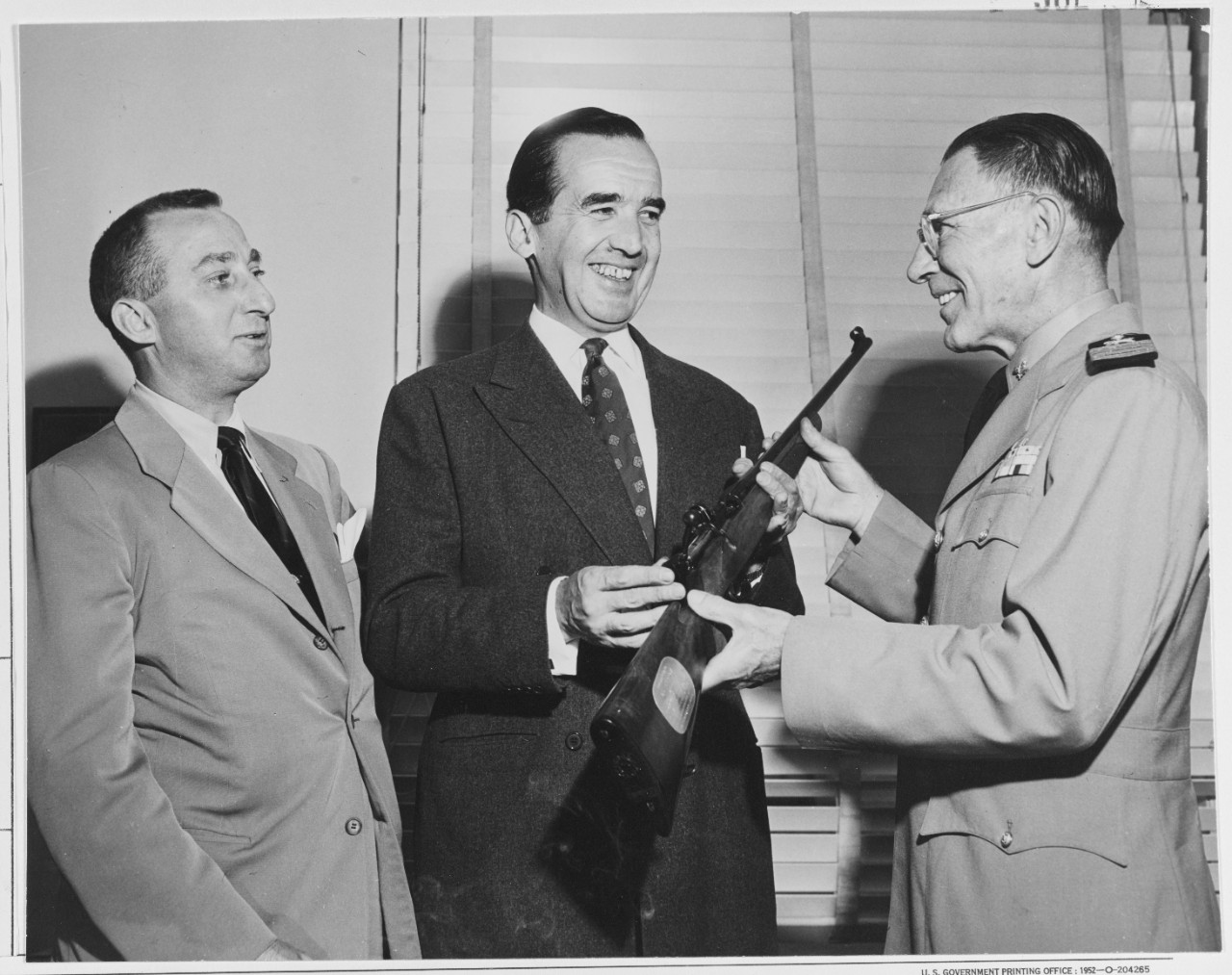 Capt Stanley A. Joy, Sc, USNR, presents a rifle to Edward R. Murrow.