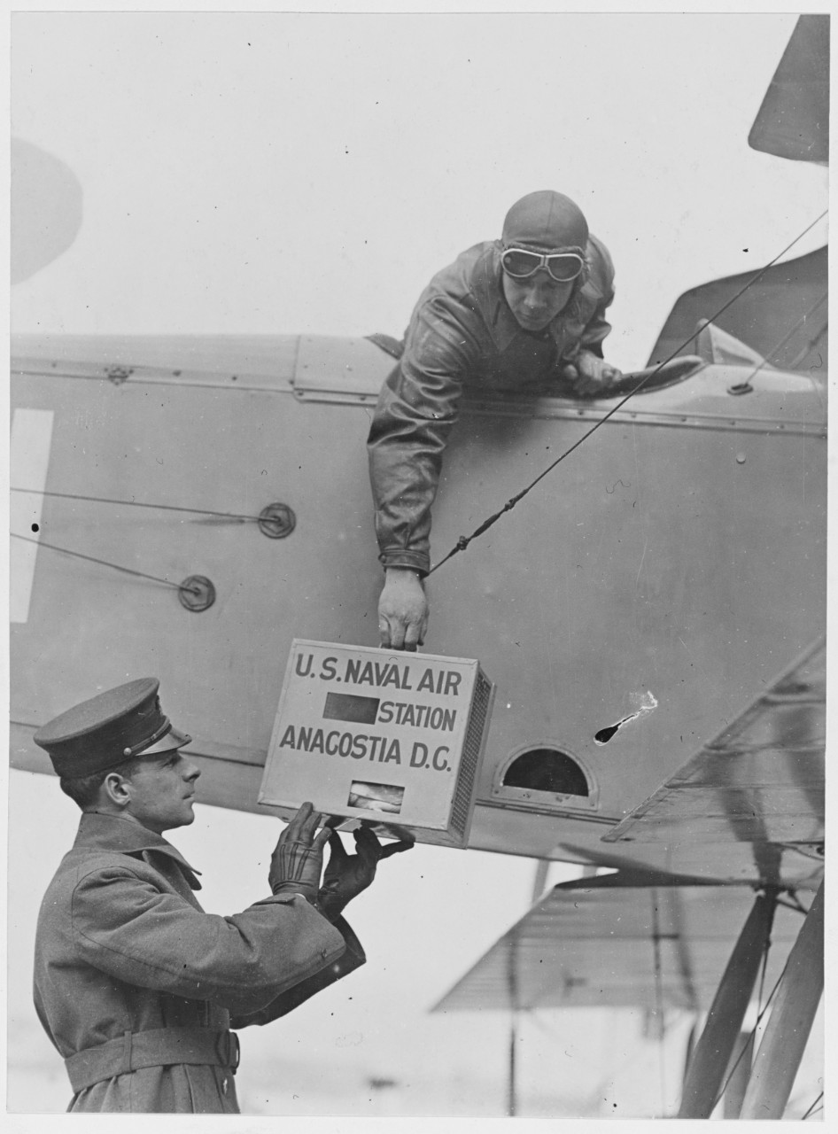 Carrier pigeons in pigeon box being handed up to pilot before leaving, U.S. Naval Air Station, Anacostia, Washington, D.C. February 12, 1919.