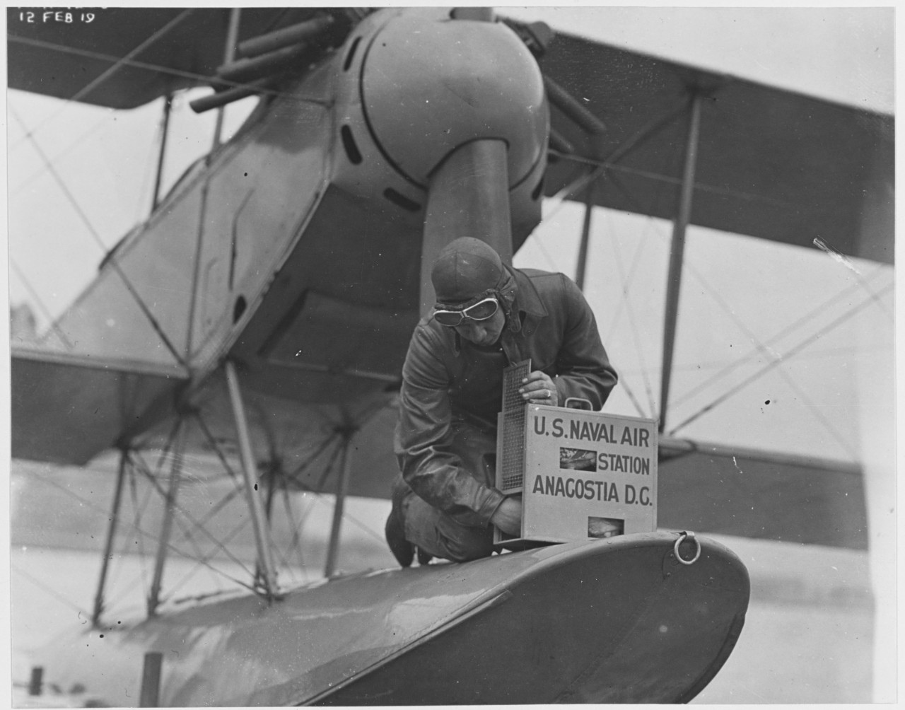 Pilot releasing carrier pigeon from pigeon box after landing, U.S. Naval Air Station, Anacostia, Washington, D.C. February 12, 1919.