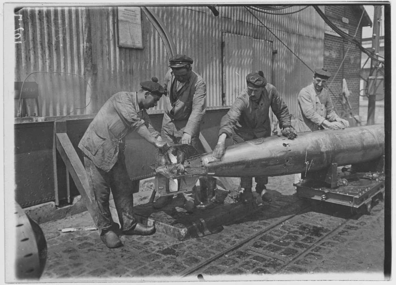 Submarine base, Cherbourg, France. Four men are working on a torpedo. Arsenal. 1918