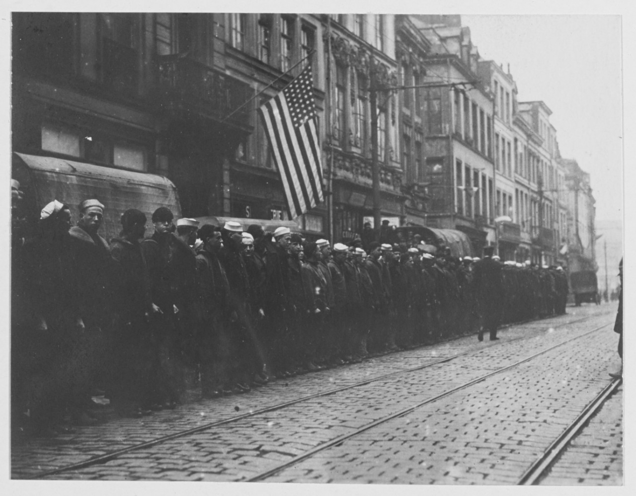 Navy men at relief headquarters, Lille, France. American flag above rows of men