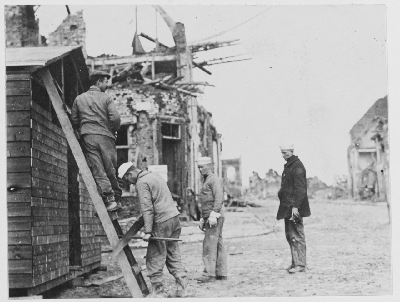 Navy relief work near Lille, France during World War I. Men building, damaged buildings in the background