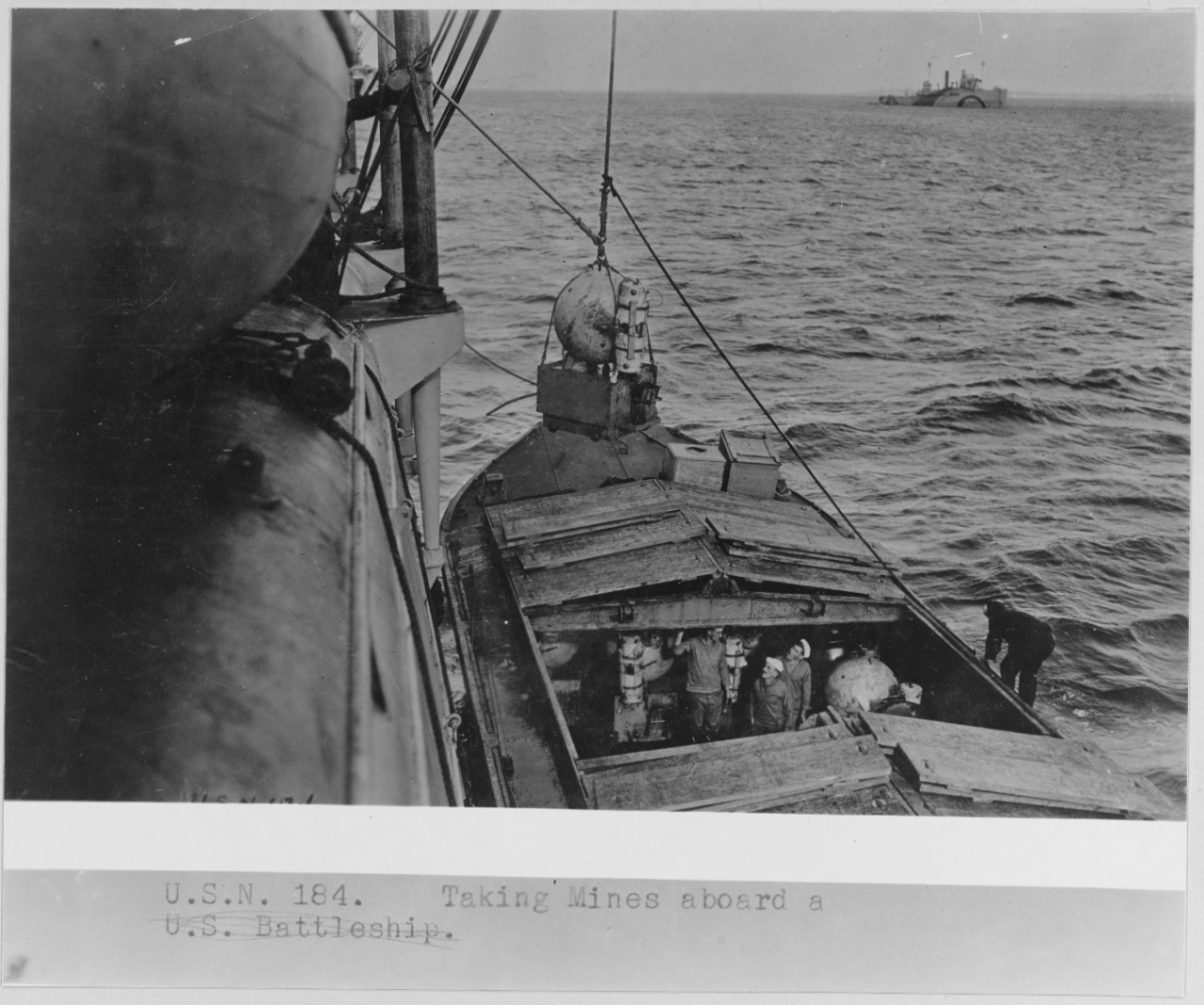 Taking mines aboard. Hoisting mines out of the barge onto a minelayer