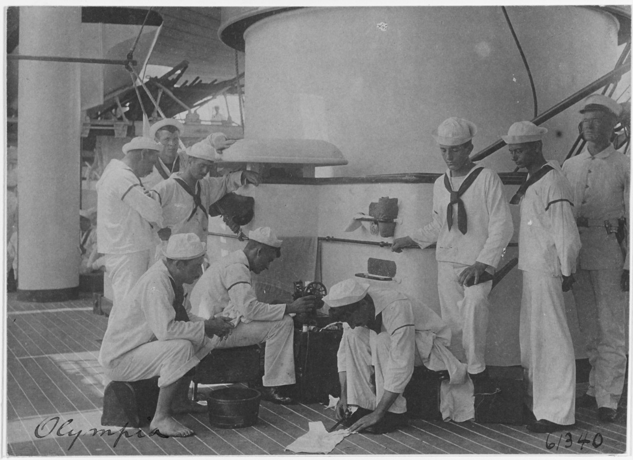 USS OLYMPIA (C-6), mending clothing on board, 1898. 