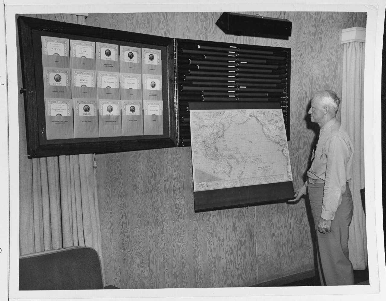 Admiral Chester W. Nimitz (CinCPac-POA) admires a wall chart case presented to him by the National Geographic Society