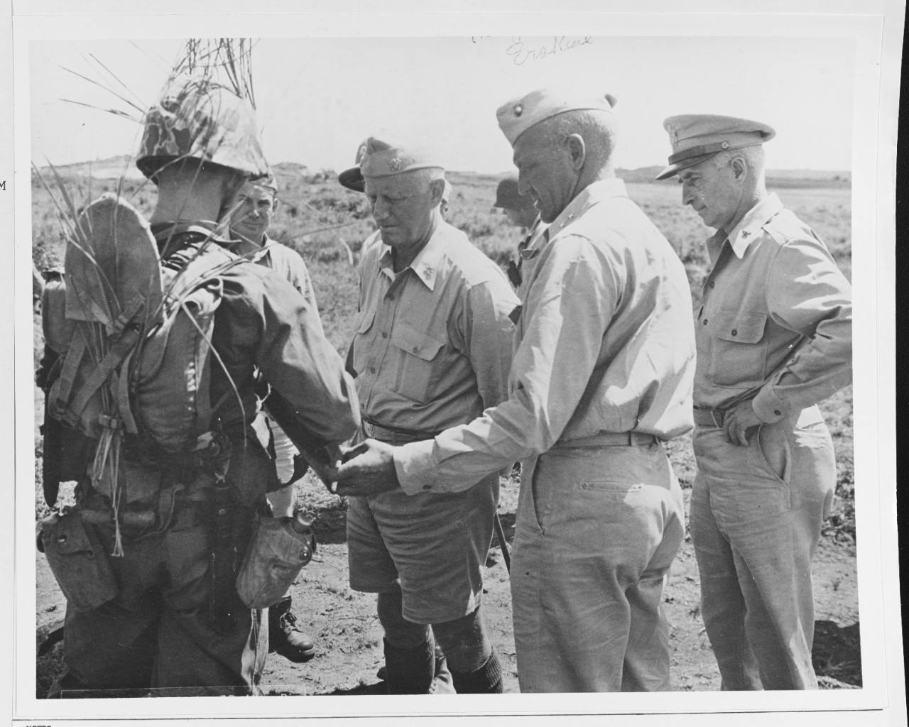 Fleet Admiral Chester W. Nimitz (CinCPac-POA), center, has the gear of a combat marine (3rd MarDiv) explained to him by MGen. G. B. Erskine, USMC.