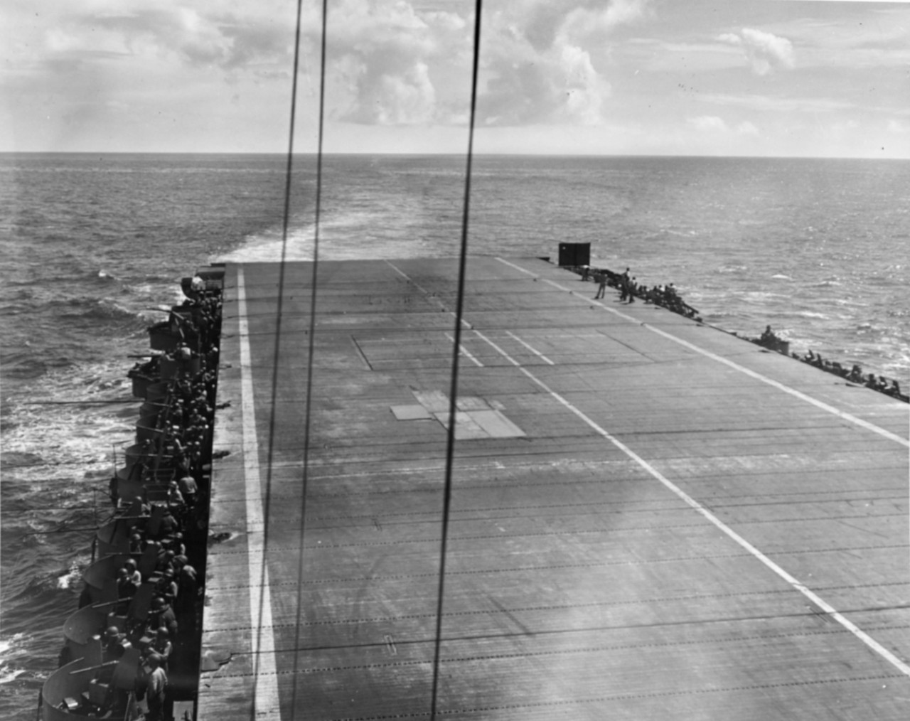 Flight deck of USS Suwannee (CVE-27) 90 minutes after a Japanese suicide plane's bomb had ripped a hole in it. Hole is patched and ship is ready to land aircraft. Note that only four wires, instead of eight, are being used. All landings were made without mishap.