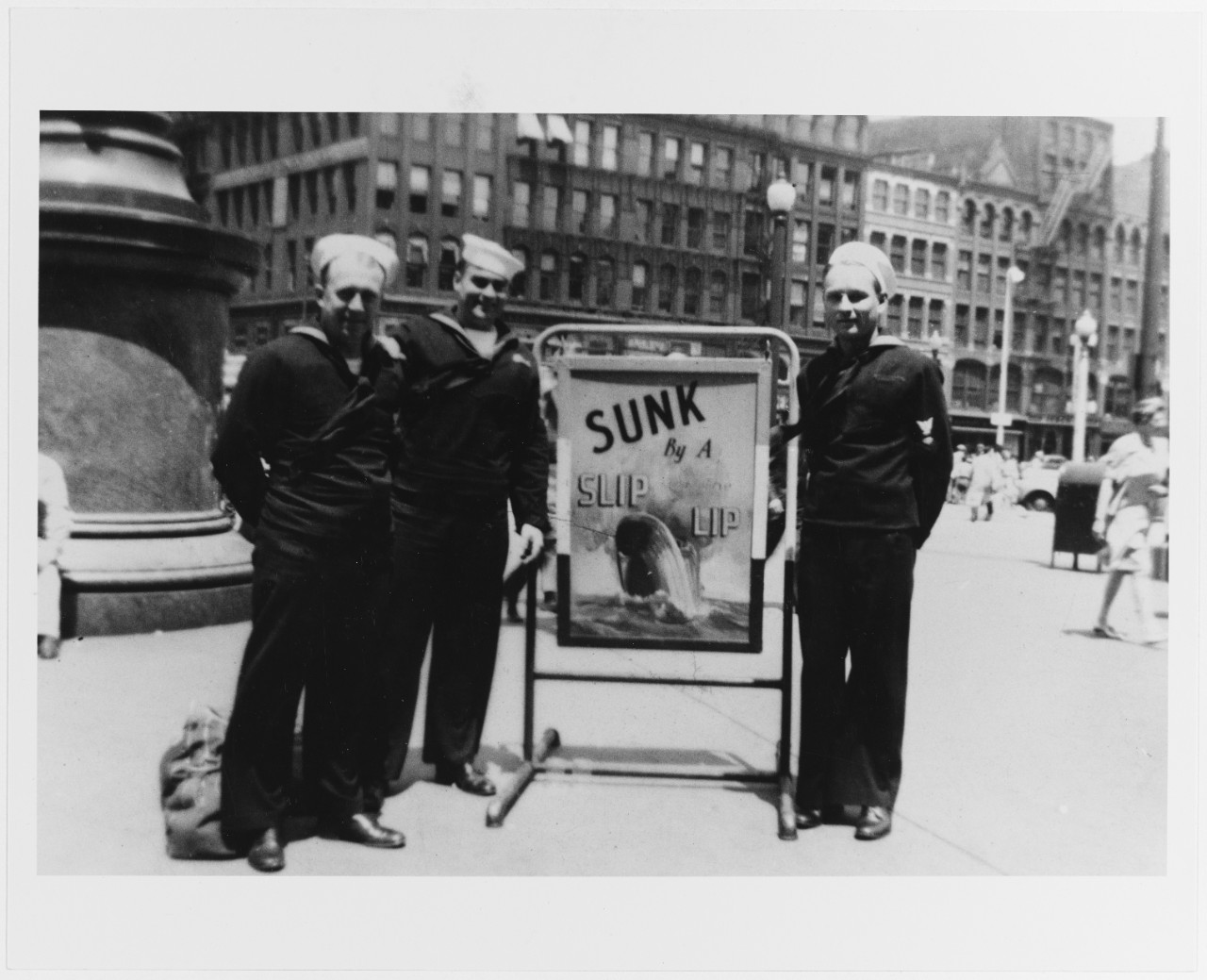 Navy men posing by a poster in Boston.