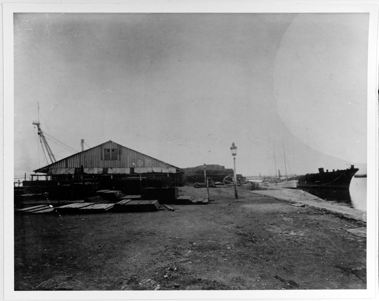 View of Storehouse off the Machina, with old coal hulk and ex-Spanish gunboat GARDOQUI alongside wharf