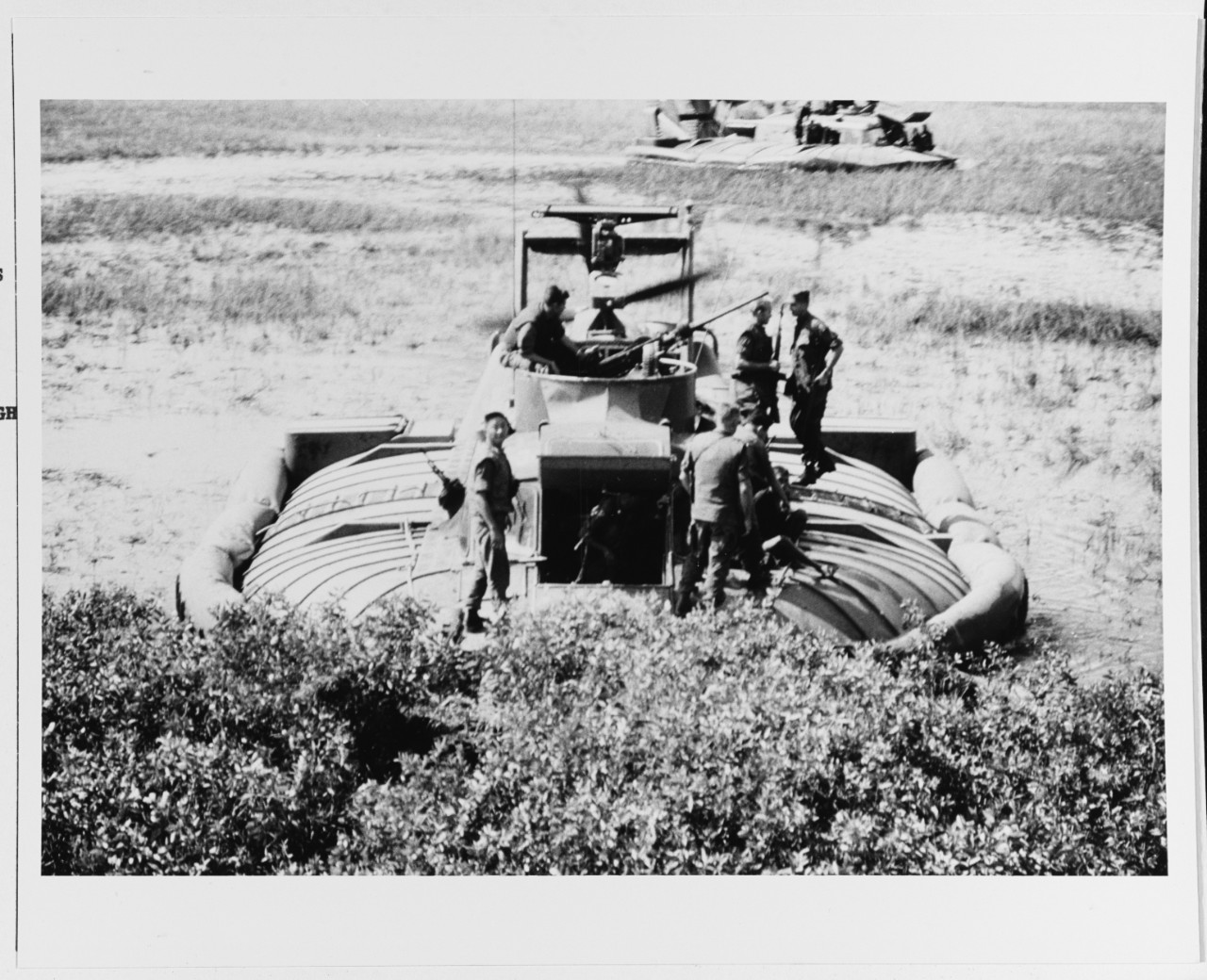 Crewmen of a PACV (patrol air cushion vehicle) and Vietnamese troops round up Viet Cong suspects