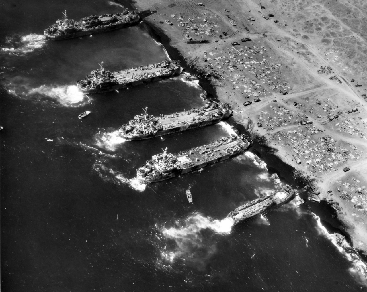 Landing ships unloading near Mt. Suribachi, 25 February 1945. Ships seen include <i>LSM-264</i>, <a href="https://www.history.navy.mil/content/history/nhhc/research/histories/ship-histories/danfs/l/lst-724.html"><i>LST-724</i></a>, <a href="https://www.history.navy.mil/content/history/nhhc/research/histories/ship-histories/danfs/l/lst-760.html"><i>LST-760</i></a>, <a href="https://www.history.navy.mil/content/history/nhhc/research/histories/ship-histories/danfs/l/lst-778.html"><i>LST-788</i></a>, and <a href="https://www.history.navy.mil/content/history/nhhc/research/histories/ship-histories/danfs/l/lst-808.html"><i>LST-808</i></a>. Image is from the Vice Admiral Calvin Durgin Photo Collection.</p>