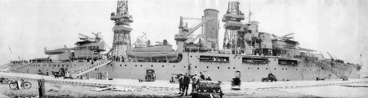 USS Oklahoma (BB-37) at pier with secondary guns exposed and men working at Norfolk Navy Yard, VA, May 1921.