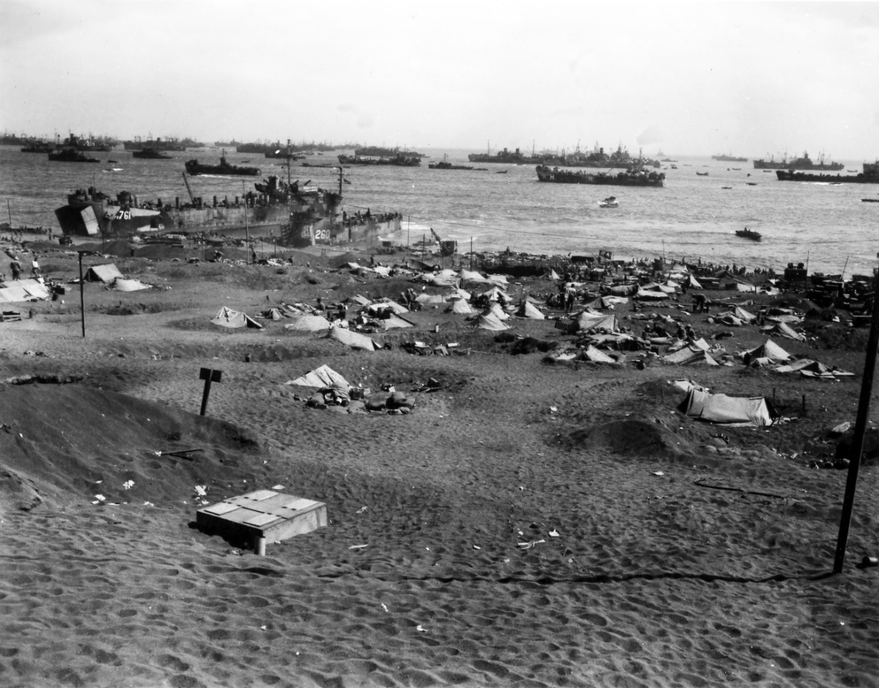 <p>Marines camp on Yellow Beach 1 on the southeastern coast of Iwo Jima on 27 February 1945. In the distance, the U.S. Coast Guard–manned <a href="https://www.history.navy.mil/content/history/nhhc/research/histories/ship-histories/danfs/l/lst-761.html"><i>LST-761</i></a> and the U.S. Navy–manned <i>LSM-260</i> are beached next to each other. Further out, an evacuation-control LST (identified by the painted letter H on her hull) remains offshore to examine and process casualties. Image is from the of Admiral Harry W. Hill Collection.</p>
