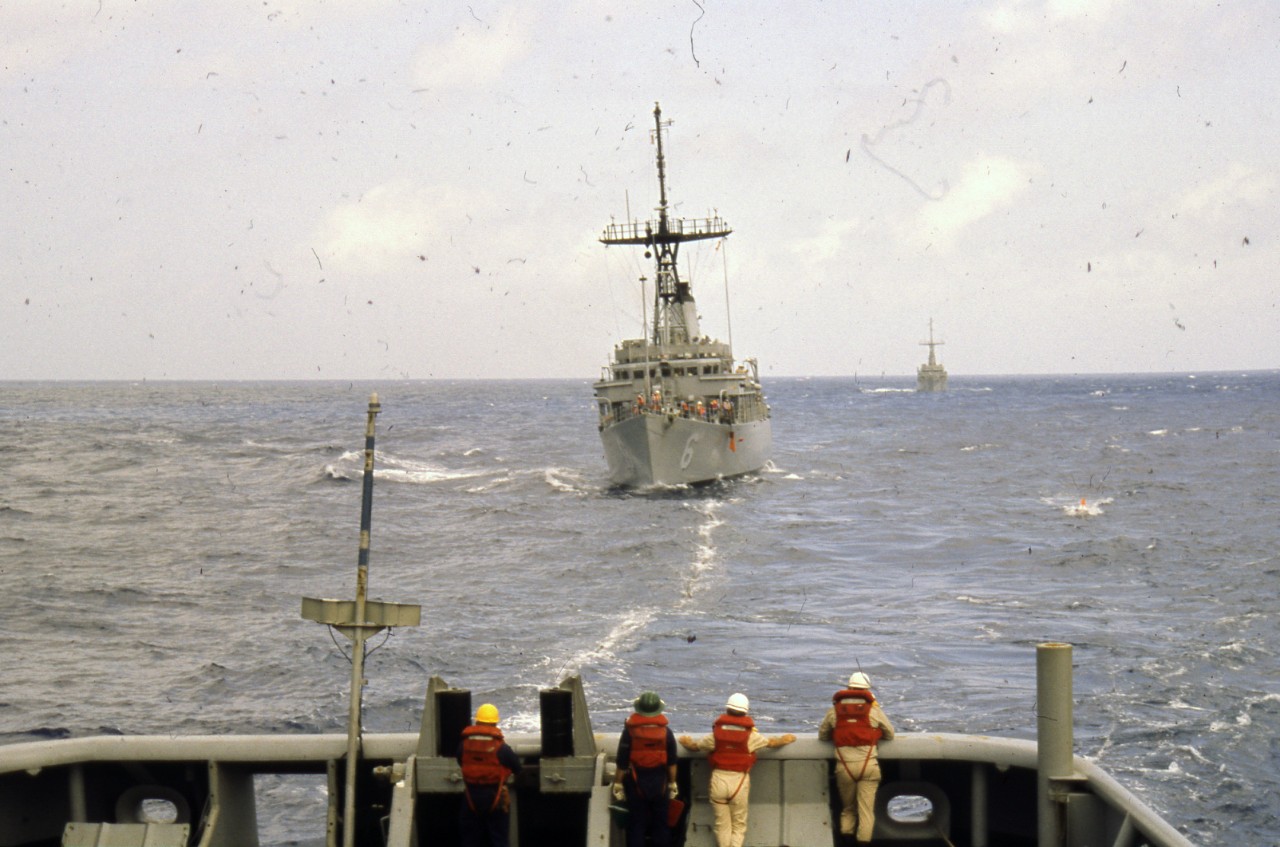 Crew on board USS Edenton (ATS-1) observe a line in the water extending back to USS Devastator (MCM-6)