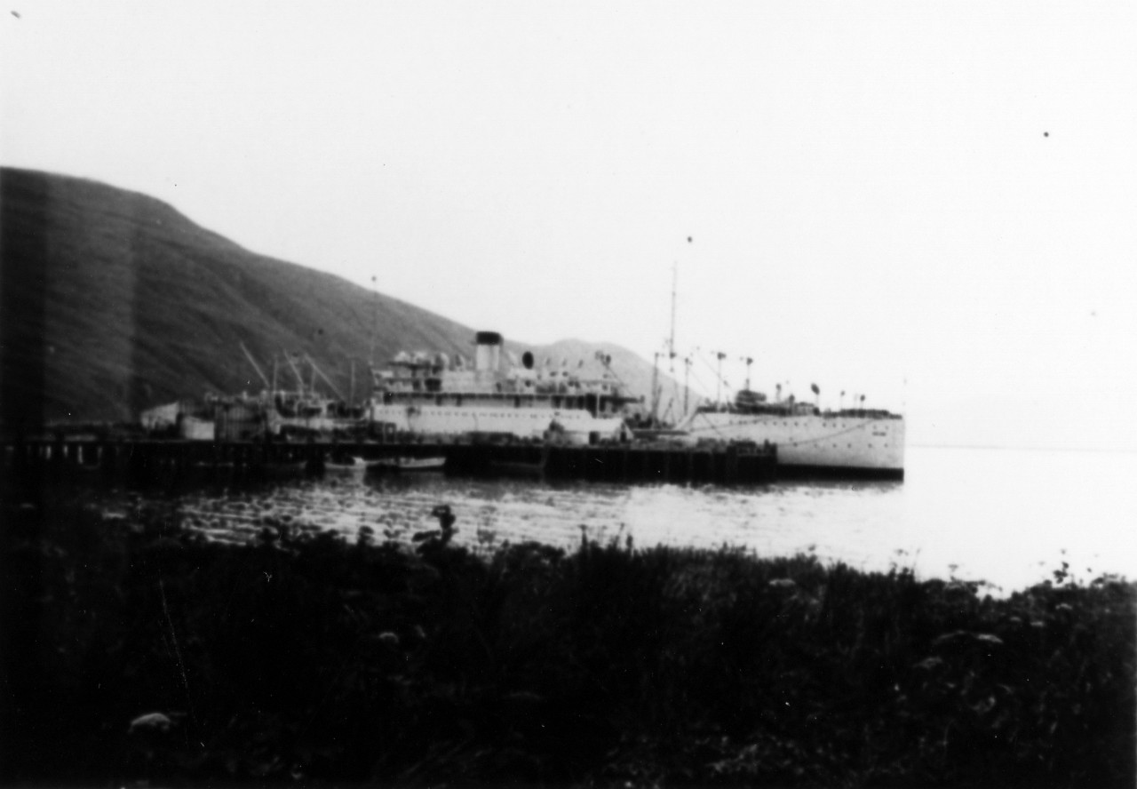 <p>UA 437.04.008 USS Argonne moored to dock at Dutch Harbor and taking fuel on board. &quot;Spit&quot; near entrance to harbor of Iliuliuk Bay, Seen apparently projecting from stern of Argonne. Entrance to harbor is beyond after deck of Argonne where hills descend.</p>
