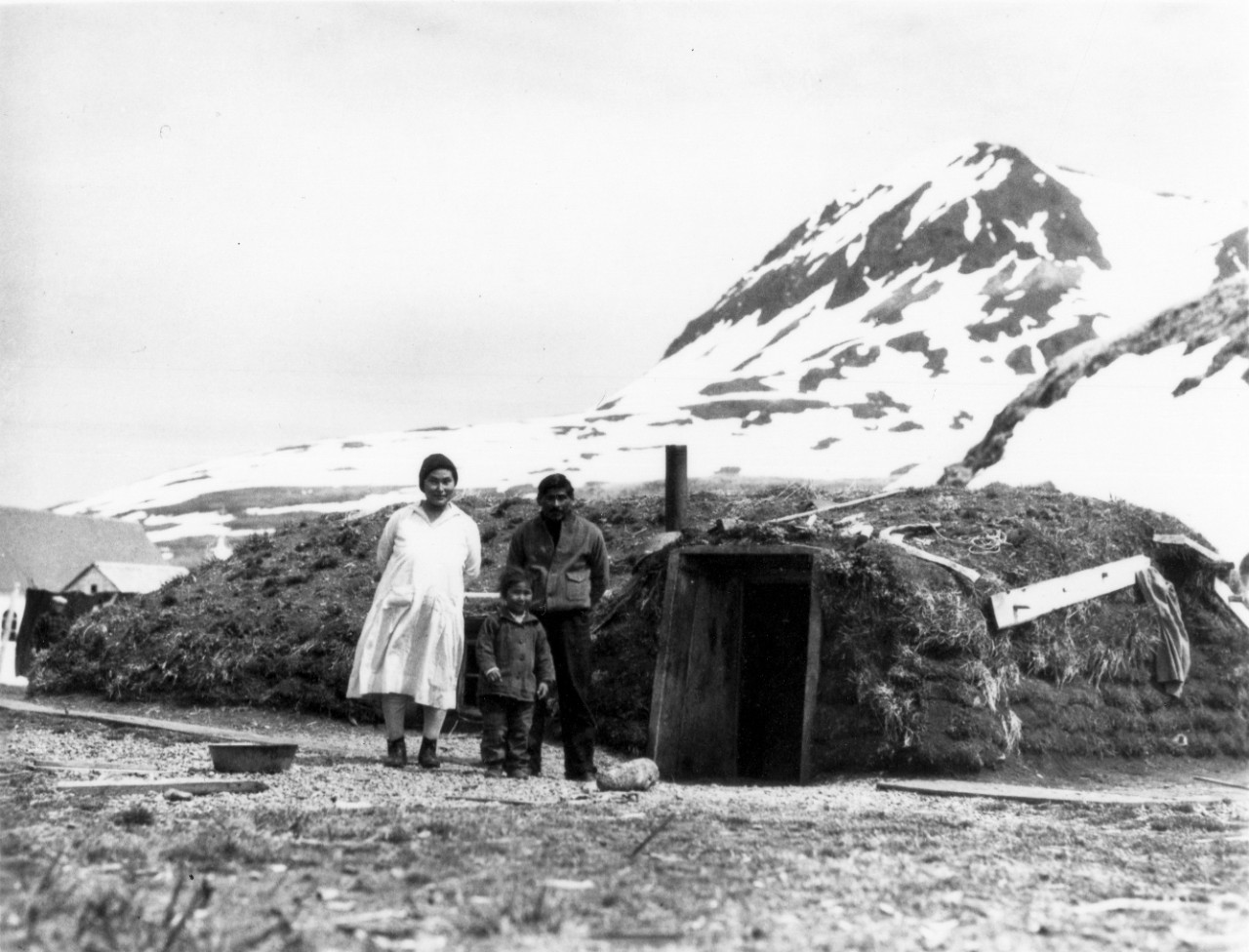 <p>UA 437.04.010 A Typical &quot;burraburra&quot; or underground dwelling used by the Aleuts. The man is Mike Hodikoff, Chief of Attu Village. In recent years the white traders have built frame houses in the islands and the &quot;burraburras&quot; are to some extent being abandodned; but they are easier to heat and safe from violent winds, and many families still prefer them.</p>
