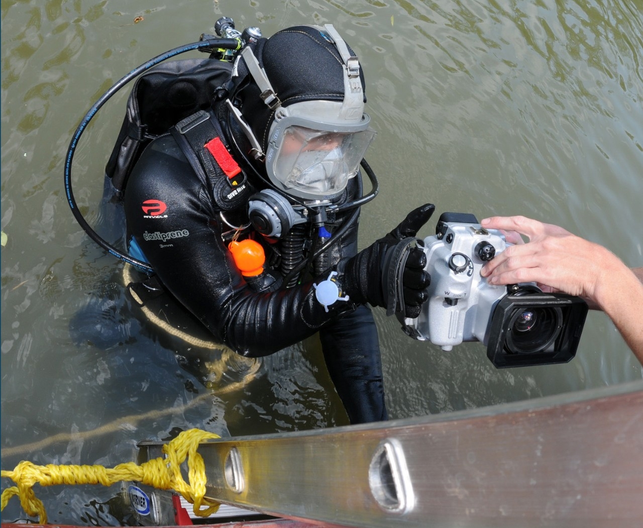 Underwater archaeologist Dr. Alexis Catsambis prepares to dive as fellow archaeologist Dr. George Schwarz hands him an underwater video camera.